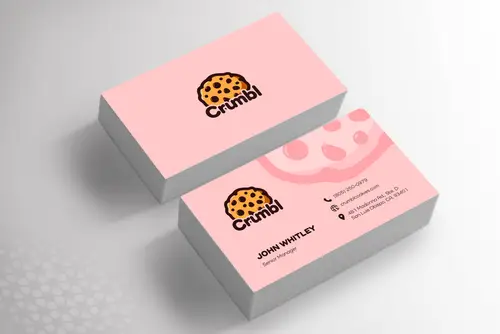Two stacks of pink business cards featuring a smiling cookie emblem and the Crumbl wordmark on a light gray surface.
